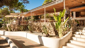 Un restaurant doté d’une terrasse, de murs en pierre et de plantes tropicales.