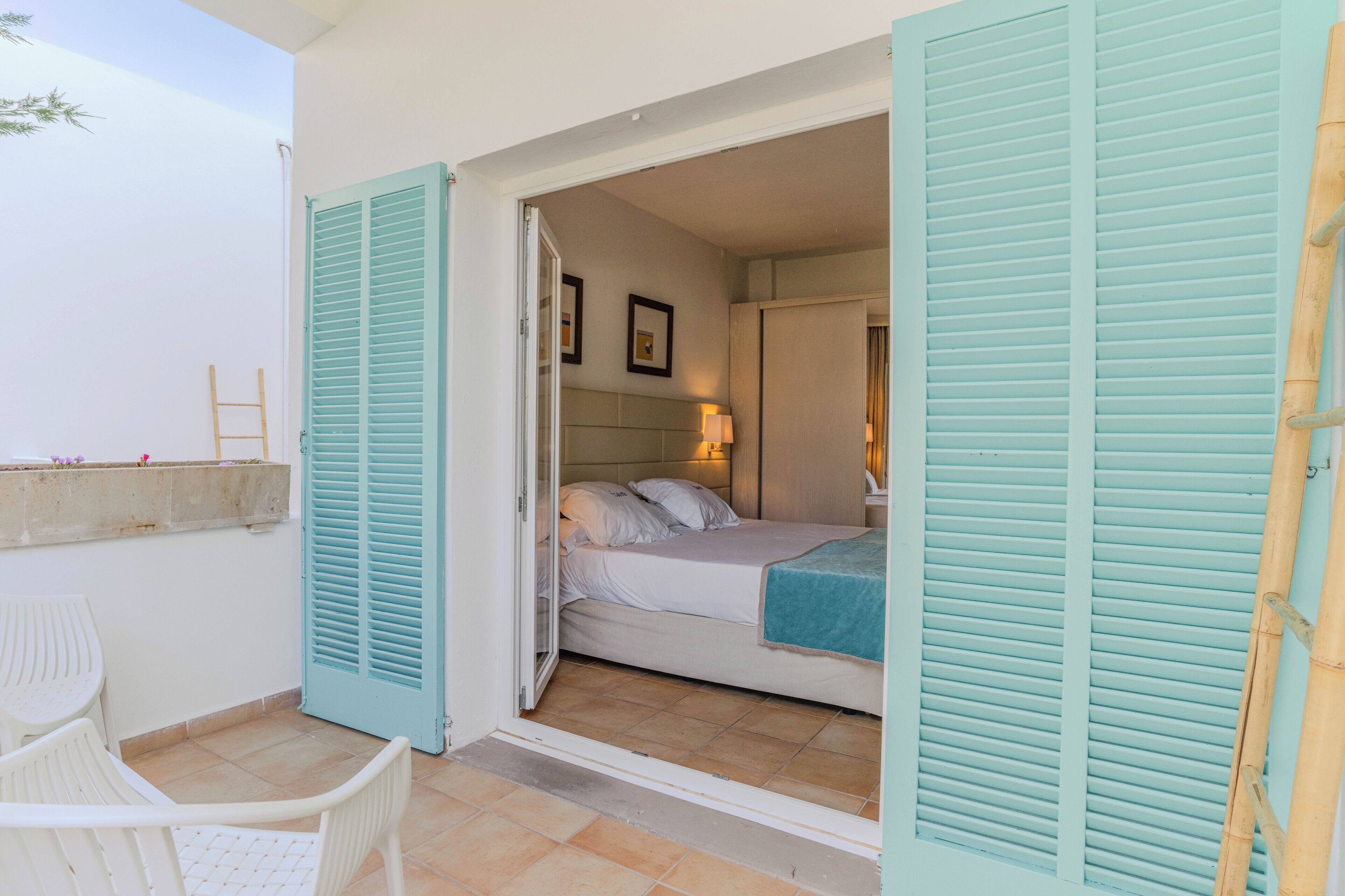A room with a bed, a chair, and a view of the outside.