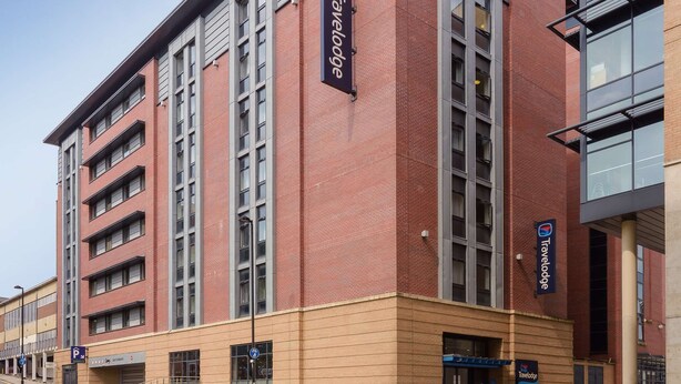 Um hotel Travelodge com fachada de tijolos, vários andares e design moderno.