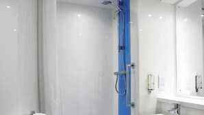 Uma casa de banho moderna com chuveiro de vidro, lavatório branco e porta-toalhas.