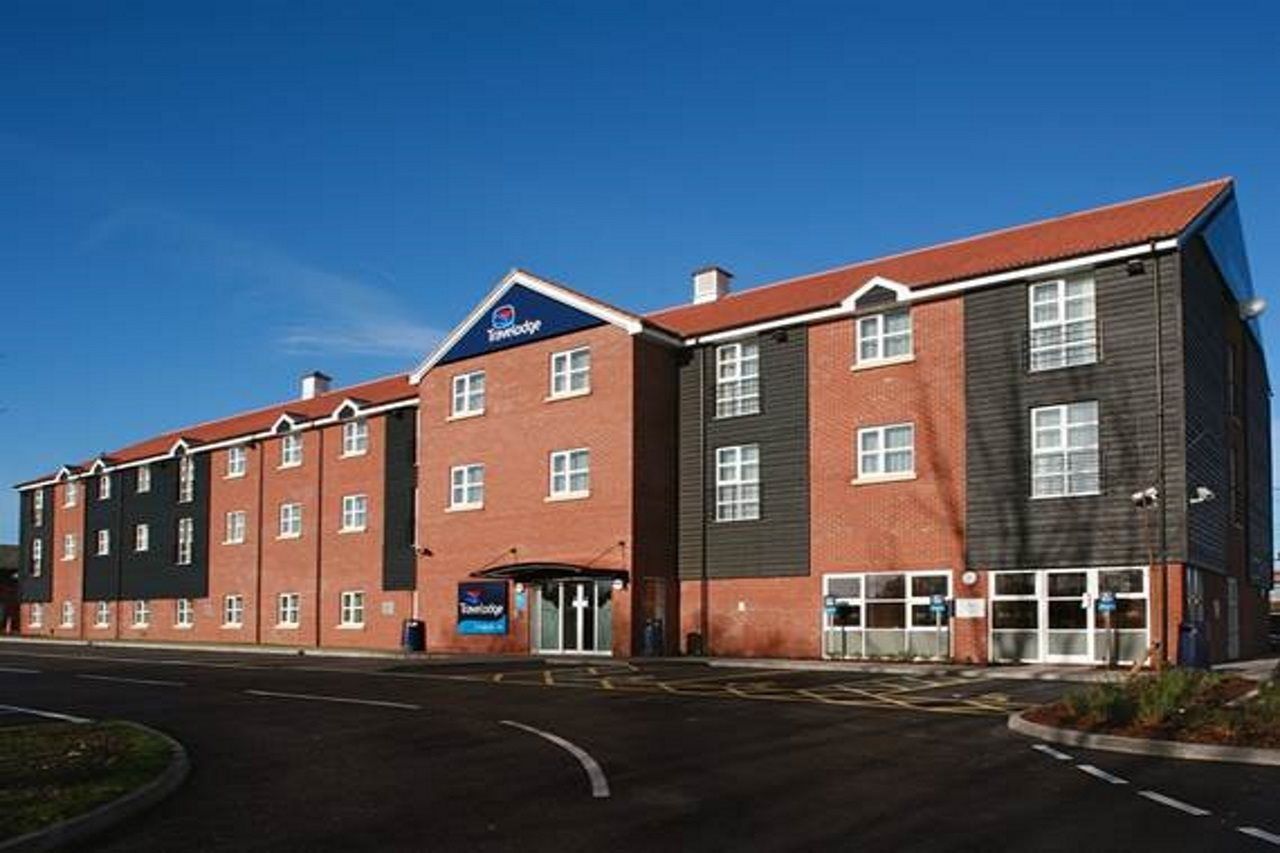 A hotel with a red brick facade, a blue sign, and a parking lot.