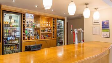 A bar area with shelves of various liquor bottles, a beer tap, and a digital display.