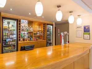 A bar area with shelves of various liquor bottles, a beer tap, and a digital display. - Travelodge Stansted Great Dunmow (Dunmow)