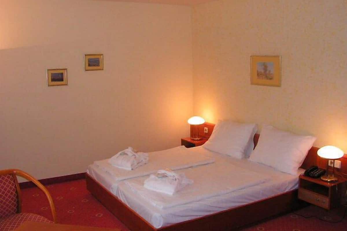 A hotel room with two beds, a chair, and bedside lamps.
