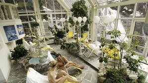 A sunlit indoor garden with stone flooring, potted plants, and yellow lounge chairs. - Hotel Sanotel (Bad Gastein)