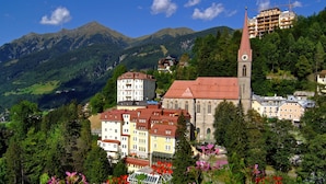 A town with a prominent church, colorful buildings, and a mountainous backdrop. - Hotel Sanotel (Bad Gastein)