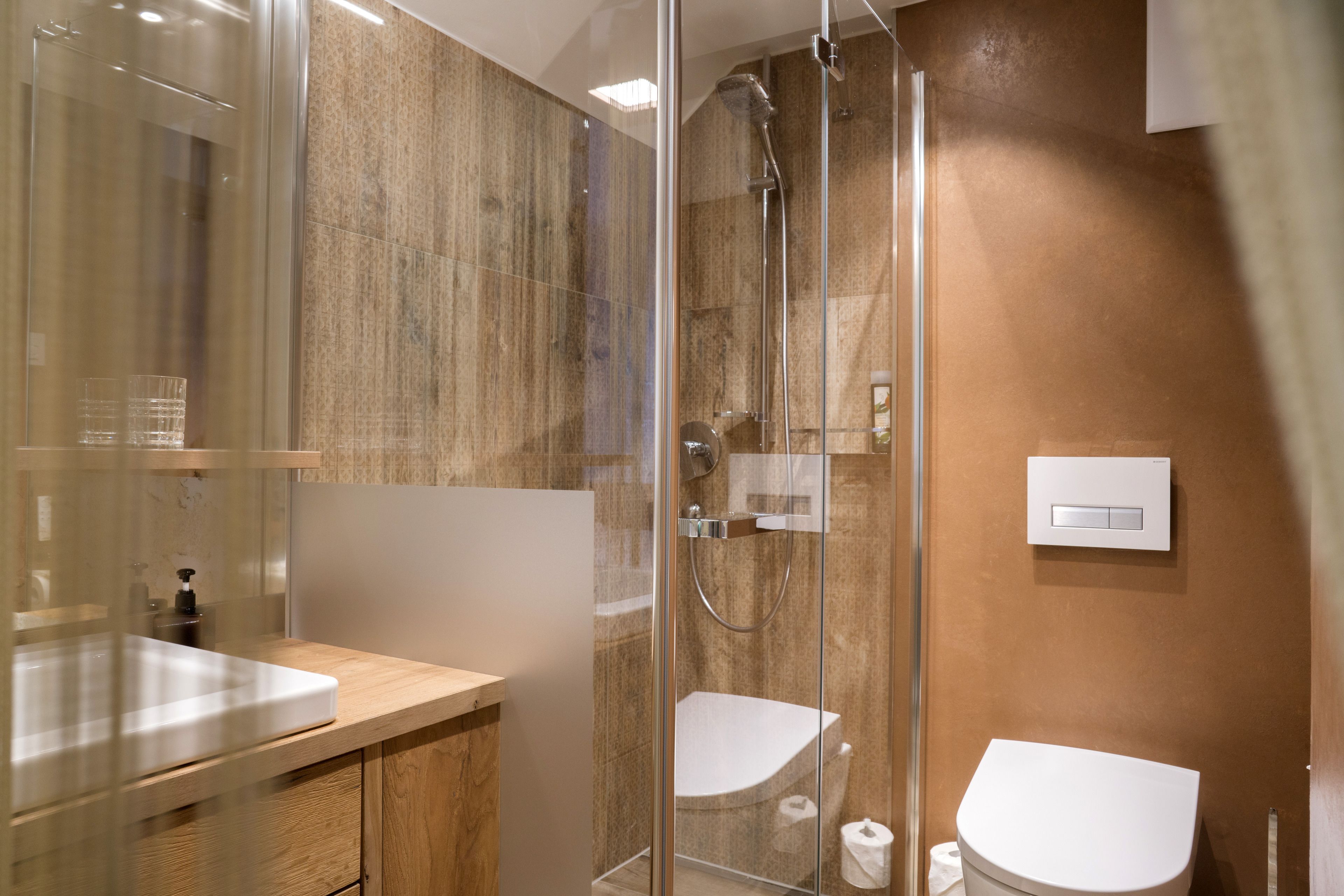 A modern bathroom with a glass shower enclosure, a wooden vanity, and a white toilet.