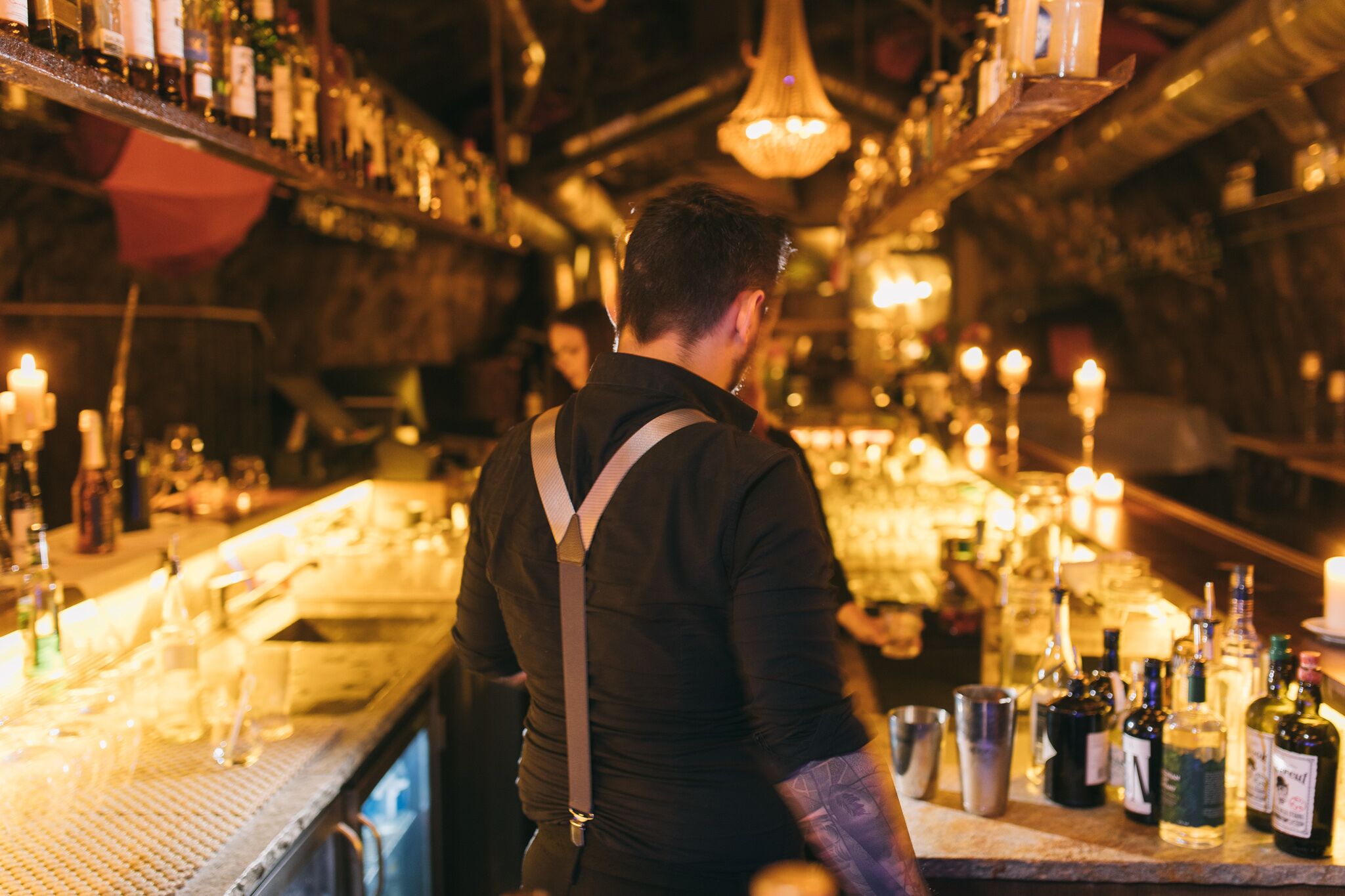 Eine Bar mit einem Barkeeper, Flaschenregalen und freundlicher Beleuchtung.