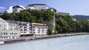 A historic castle on a hill with a river in the foreground. - Boutique Hotel im Auracher Löchl (Kufstein)
