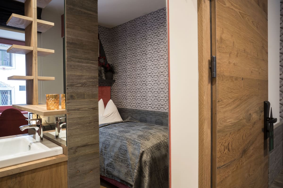 Ein modernes Schlafzimmer mit einem Holzkopfteil, einem Nachttisch mit Lampe und einem großen Fenster.