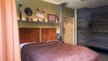 A bedroom with a bed, a shelf with decorative items, a wooden headboard, and a wall with a textured pattern.