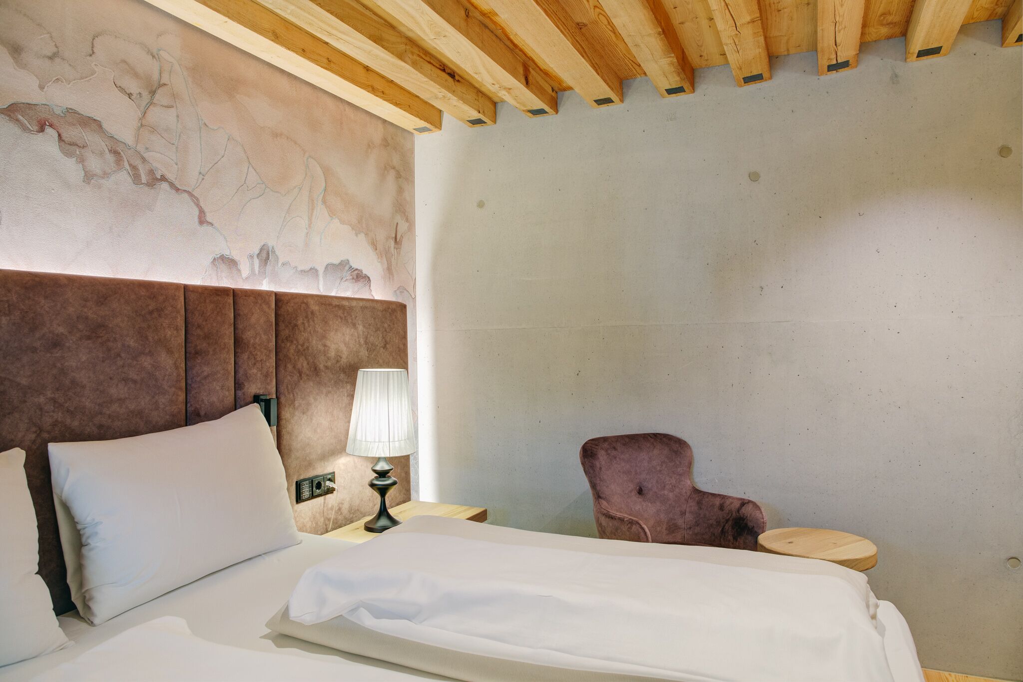 Une chambre d’hôtel avec un lit, une table de chevet, une lampe et une chaise.