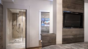 Un dormitorio moderno con cabecera de madera, televisión integrada y zona de ducha.