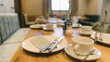 A dining table set with plates, cutlery, and a cup, with a blurred background suggesting a cozy indoor setting.