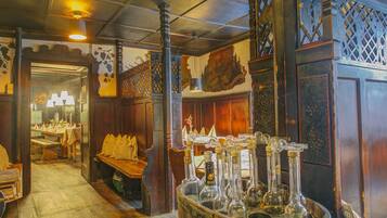 A vintage interior with wooden furniture, a barrel of bottles, and a decorative wall.