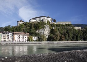 Un castillo histórico en una colina, con un río en primer plano.