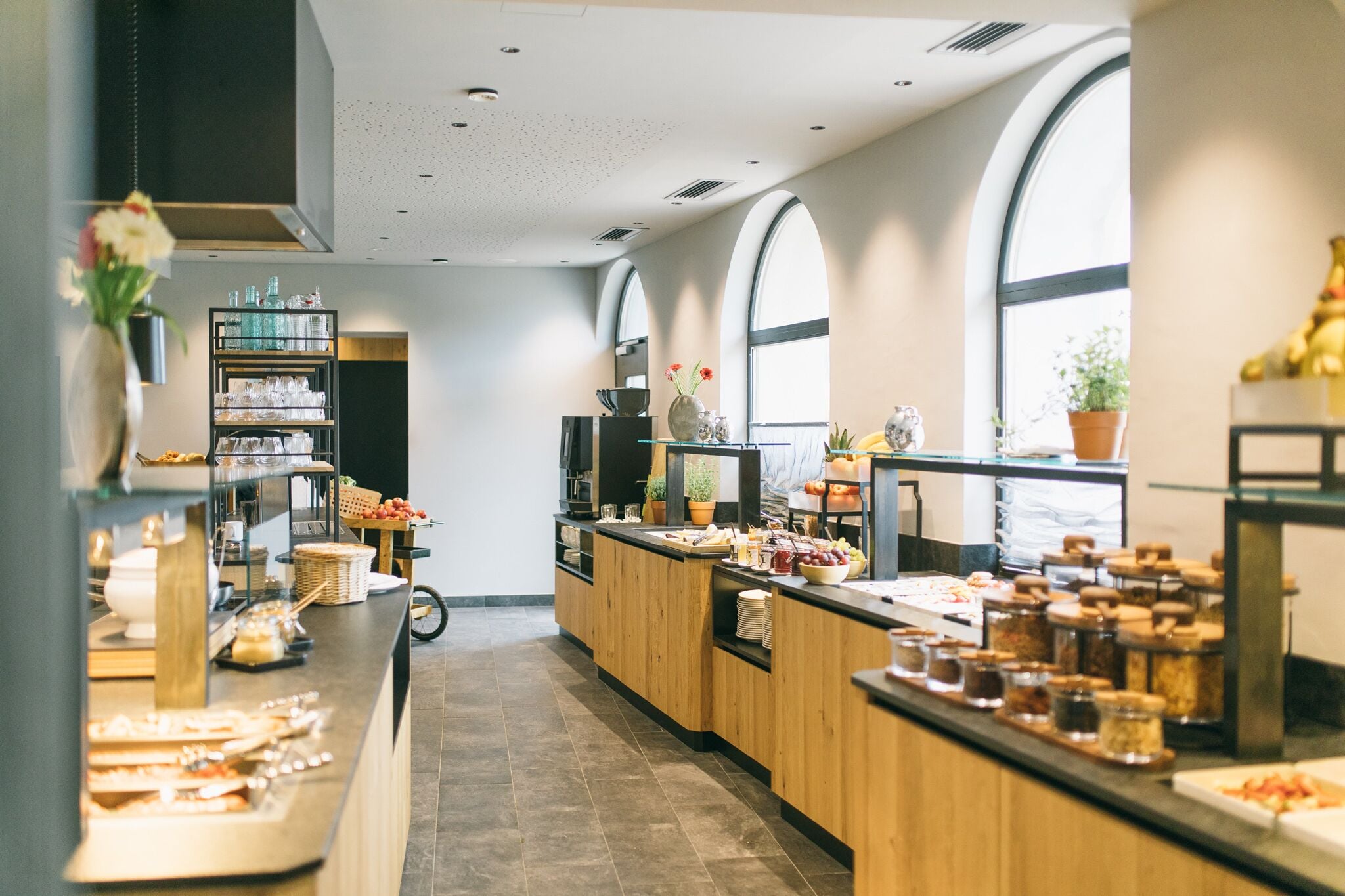 Una barra de petitdejuni moderna amb diverses opcions gastronòmiques, un espai per al cafè i vistes a la ciutat a través de grans finestres.