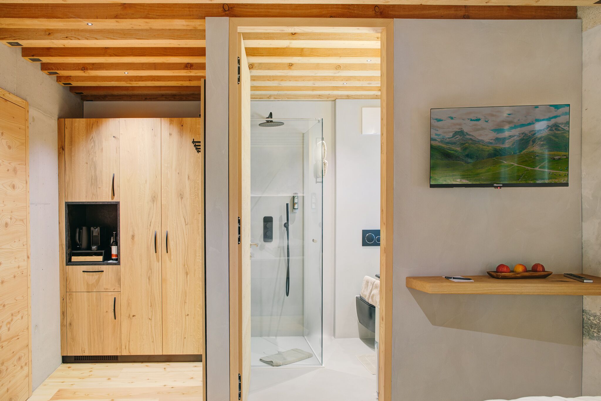 Een moderne badkamer met een glazen douchecabine, houten kasten en een hangend kunstwerk.