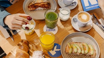 A breakfast setting with croissants, a croissant sandwich, a plate of sliced avocado, a cup of coffee, and a glass of orange juice.