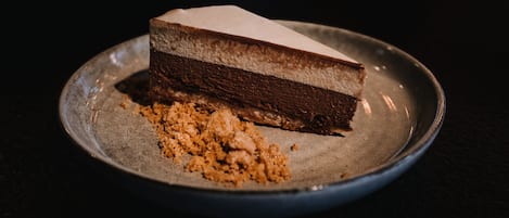 Una porción de pastel de chocolate en capas sobre un plato, con migas a un lado.