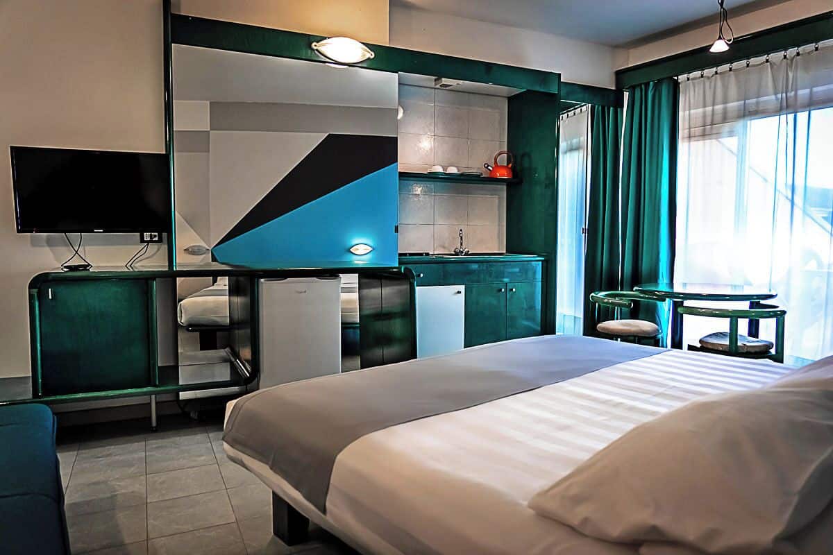 Une chambre d’hôtel équipée d’un lit, d’une télévision, d’une petite kitchenette et d’une salle de bain.