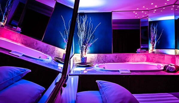 A modern spa room with a large mirror, a massage table, and a small seating area. - Business Hotel (Casale Monferrato)