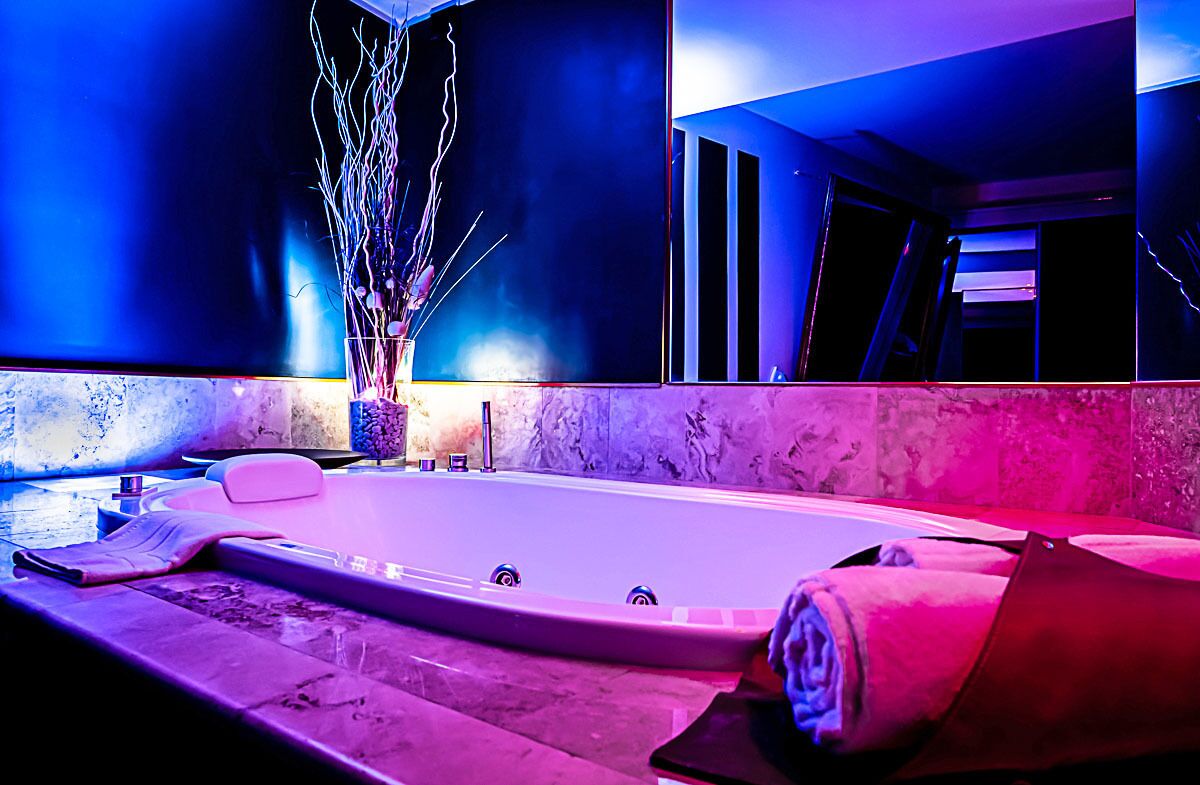 Une salle de bain moderne avec une grande baignoire, des murs en marbre et un miroir.