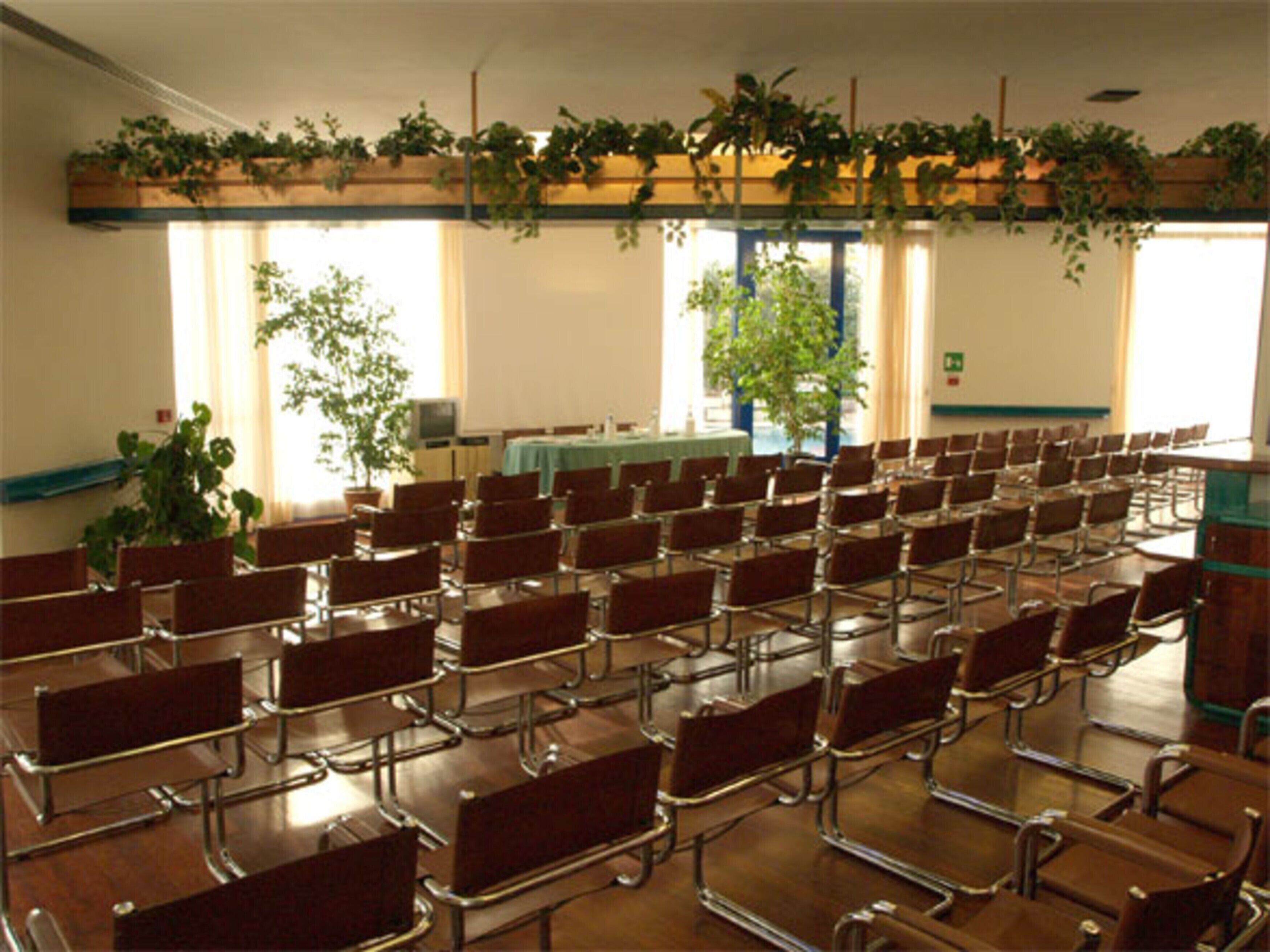 A conference room with rows of chairs, a projector screen, and a table with a green tablecloth.