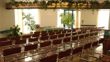 A conference room with rows of chairs, a projector screen, and a table with a green tablecloth.