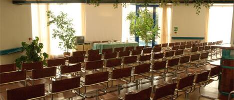 A conference room with rows of chairs, a projector screen, and a table with a green tablecloth.