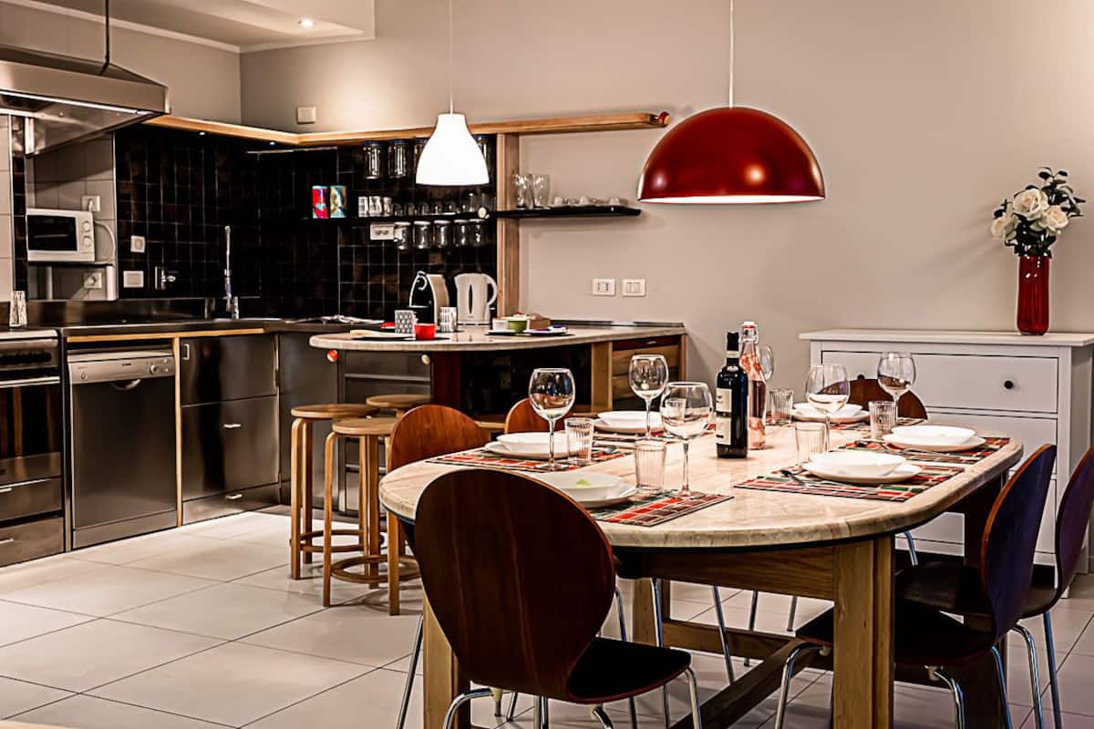 Une cuisine moderne avec un coin repas, équipée d’un four à micro-ondes, d’un four et de divers appareils de cuisine.