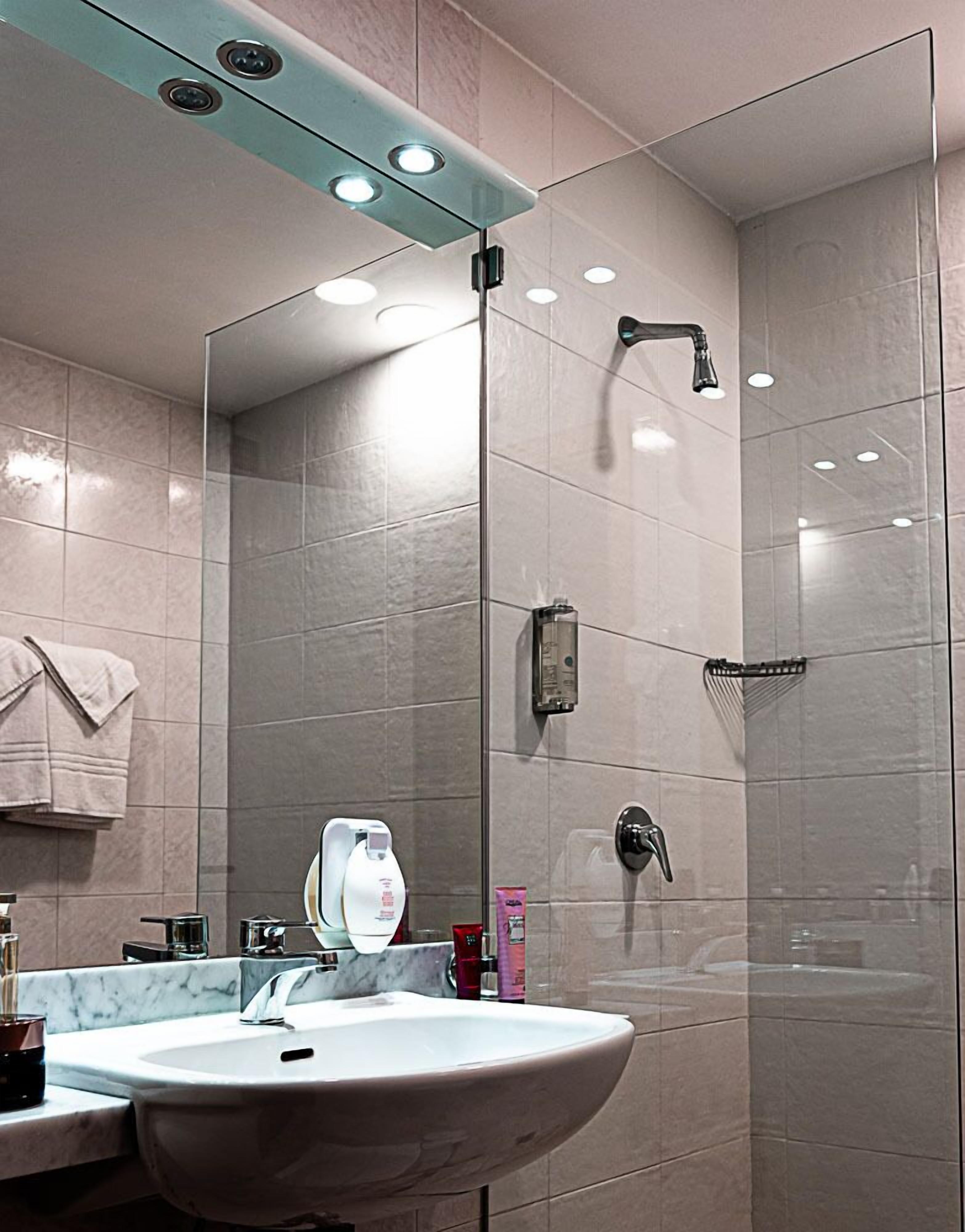 A modern bathroom with a glass shower enclosure, a marble sink, and a towel rack.
