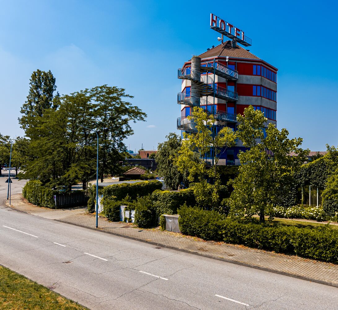 A multi-story hotel with a distinctive red and blue facade, balconies, and a clear blue sky.