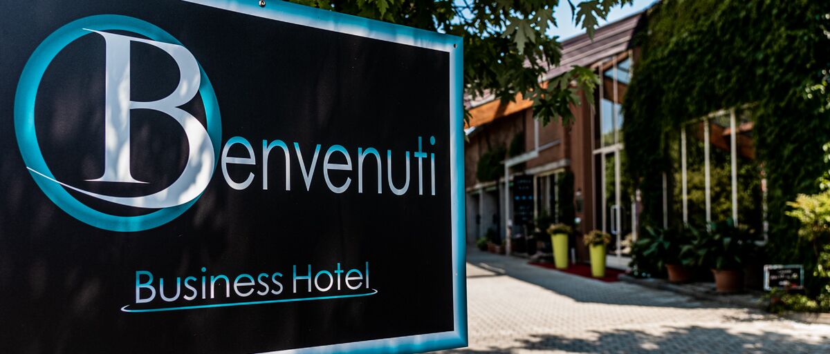 Une enseigne pour l’hôtel d’affaires Benvenuti, avec un logo bien visible et le nom de l’hôtel.