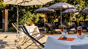 An outdoor dining area with tables, chairs, and umbrellas. - Business Hotel (Casale Monferrato)