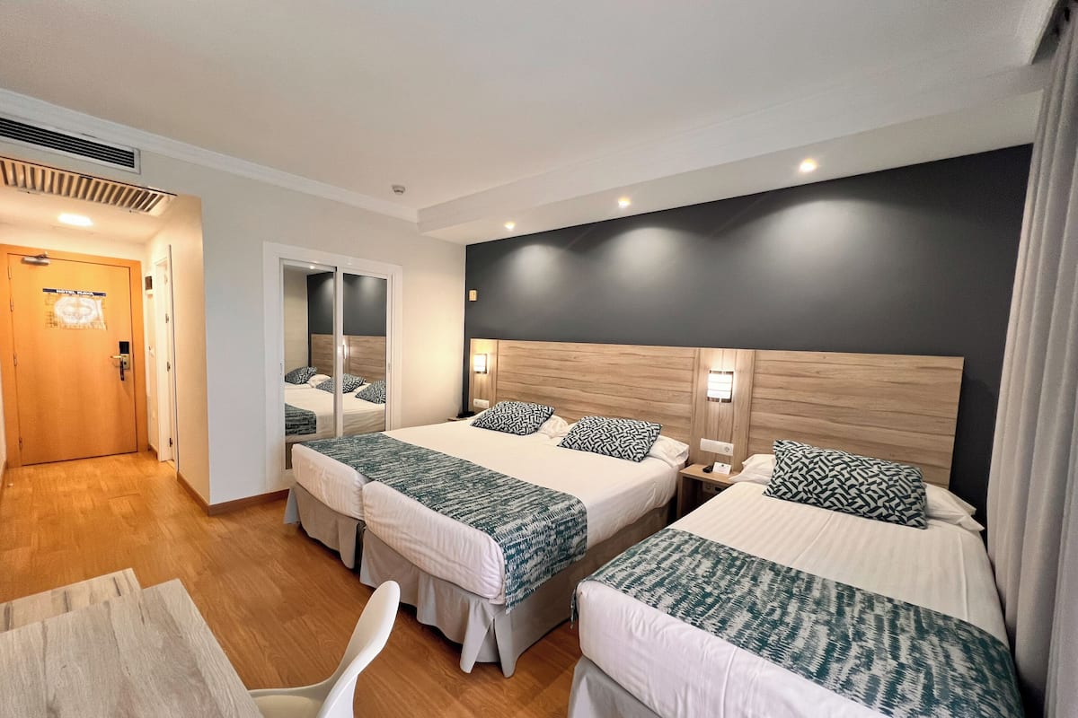 Una habitación de hotel con dos camas, un escritorio y una silla.
