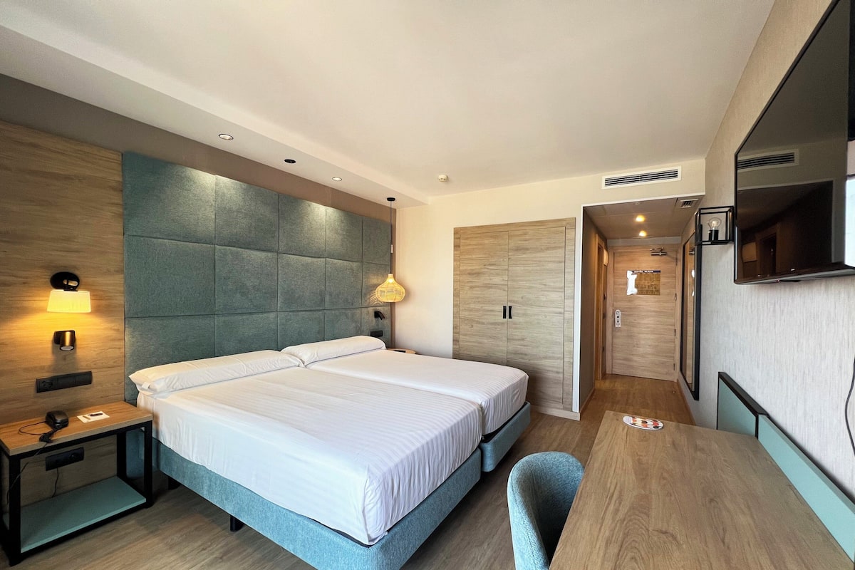 Ein modernes Hotelzimmer mit einem großen Bett, einem Schreibtisch und einem Fernseher.