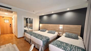 A hotel room with two beds, a desk, and a chair.
