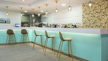 A bar area with a light blue counter, wooden stools, and hanging pendant lights.