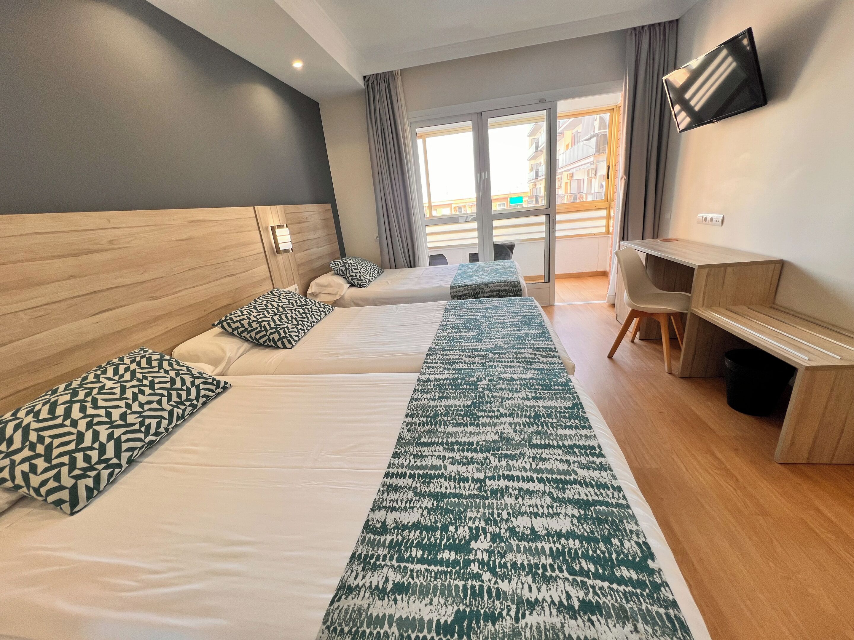 Une chambre d’hôtel moderne équipée de deux lits, d’un bureau et d’une télévision.