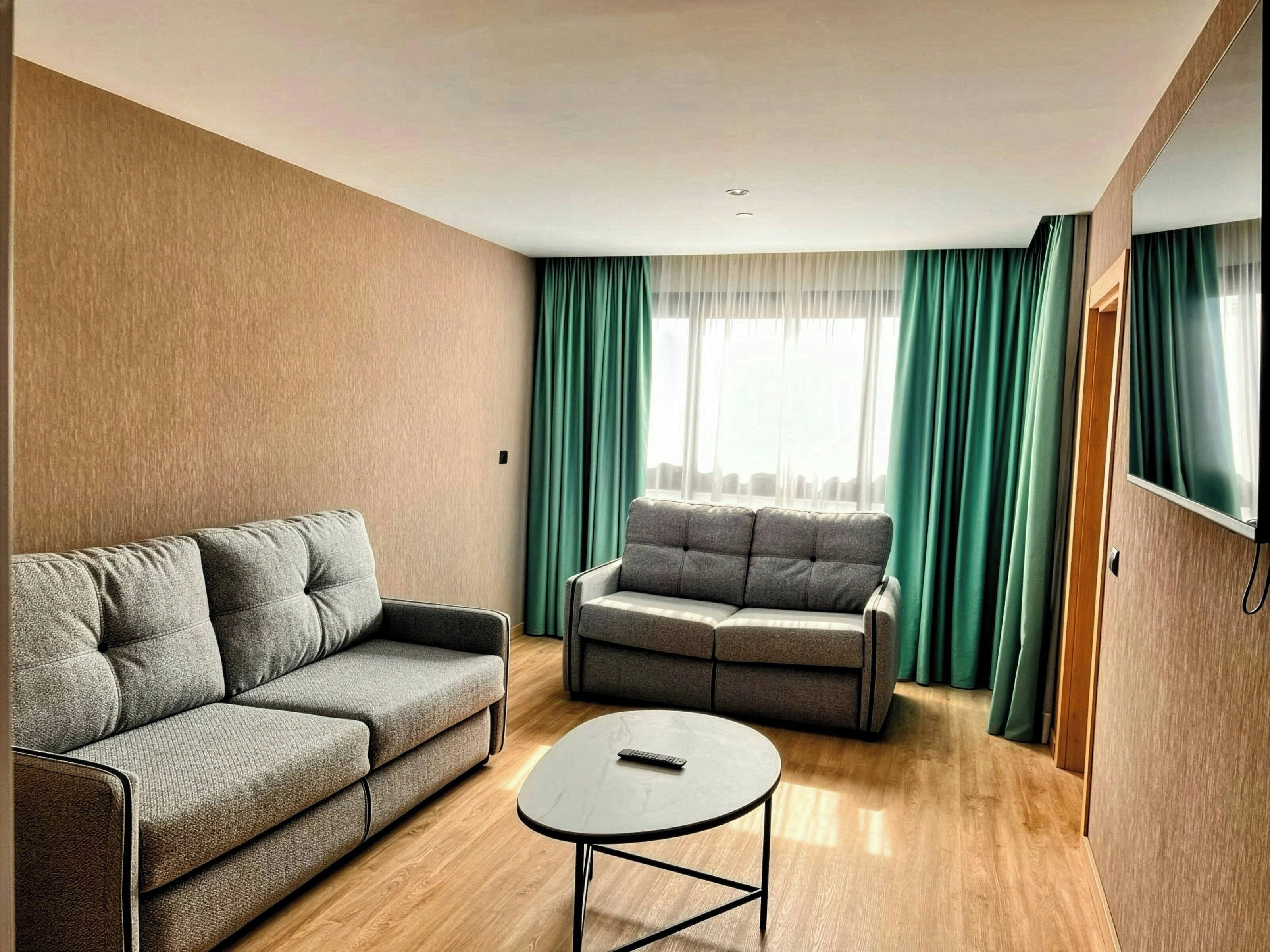 Una sala moderna con un sofá, un sillón más pequeño y una mesita de centro.