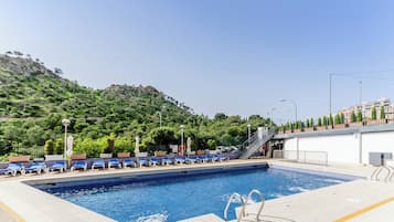 Una piscina al aire libre de temporada, sombrillas, tumbonas