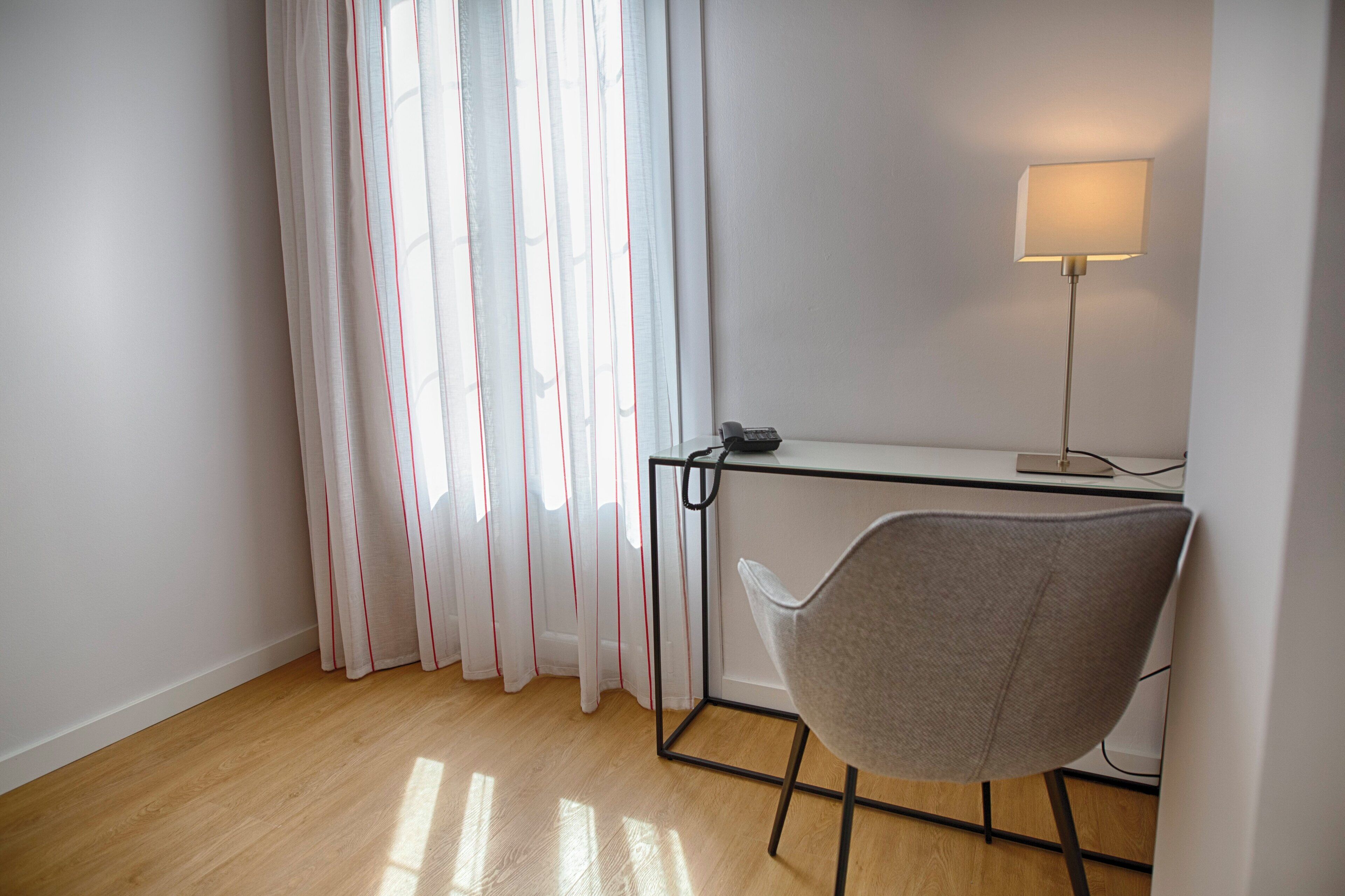 Una habitación con un escritorio, una silla y una lámpara.