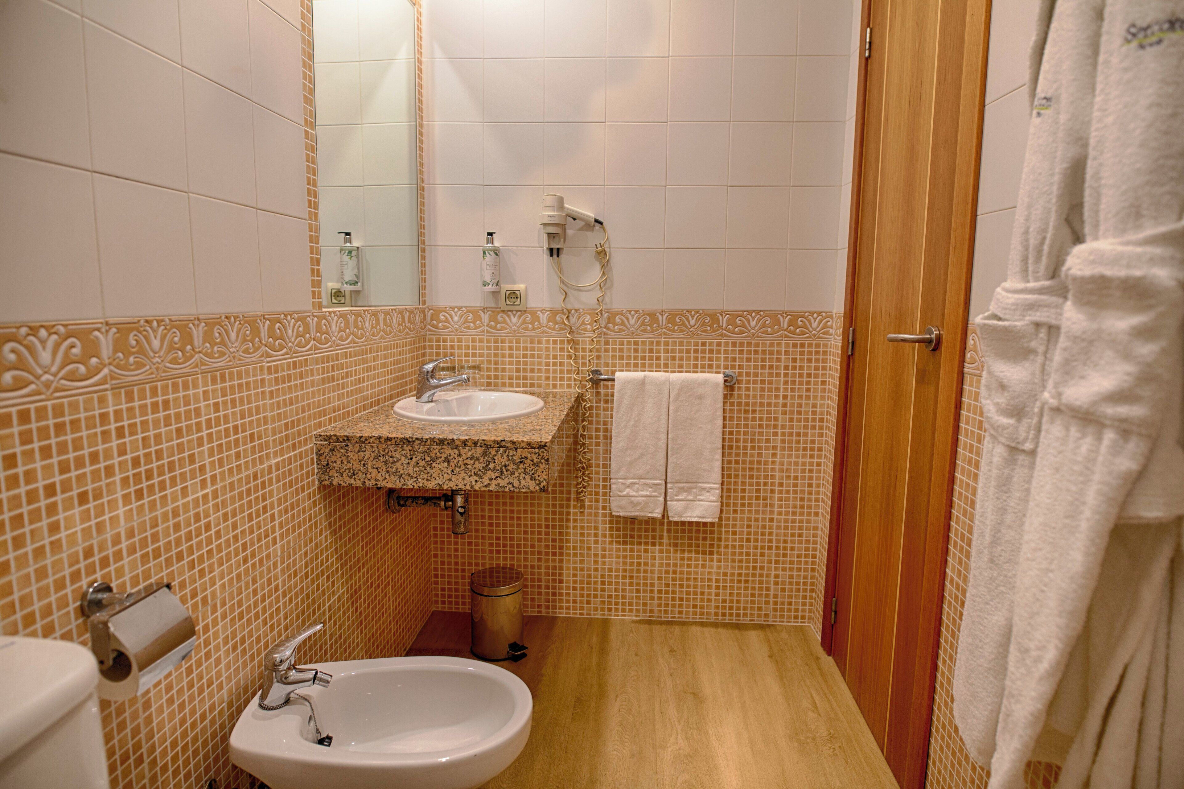 Un baño con lavamanos, espejo y ducha.