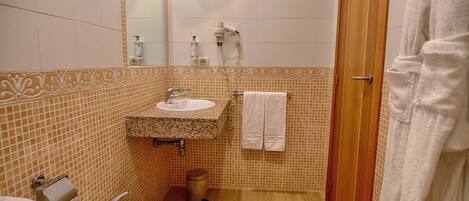 Un baño con lavamanos, espejo y ducha.