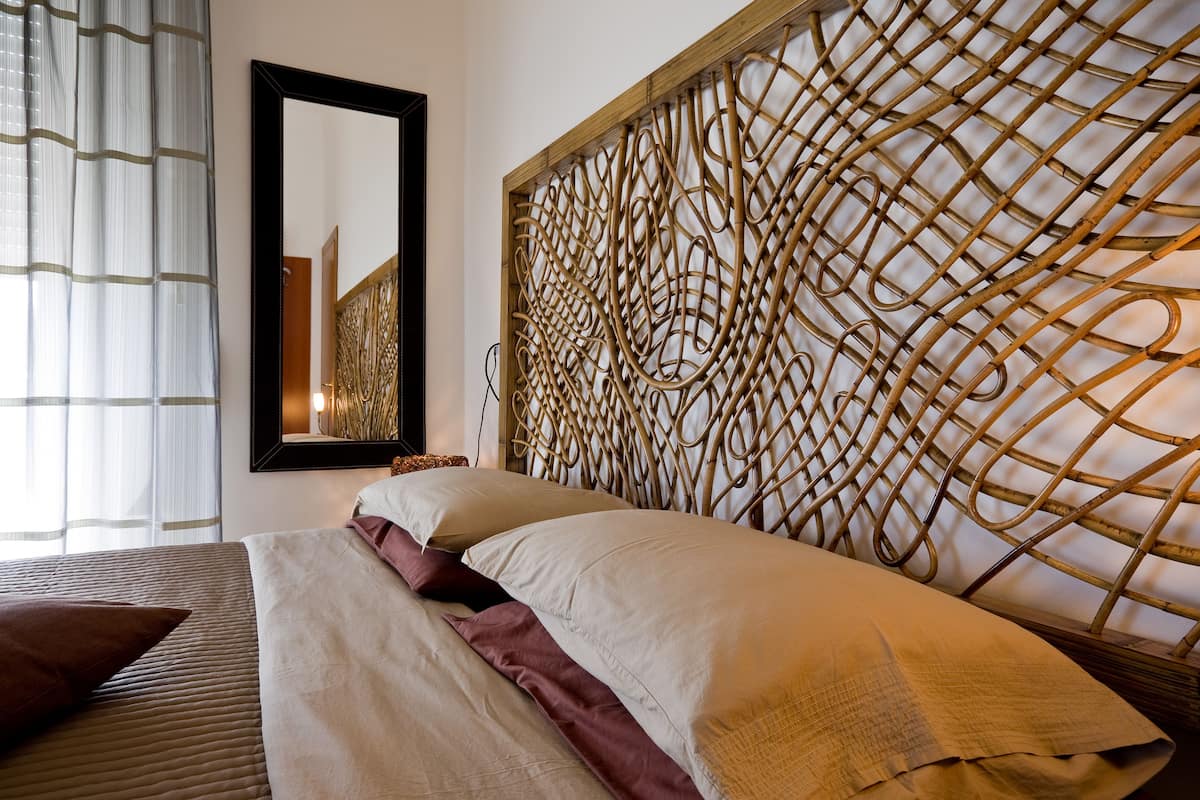 A hotel room with a bed, a large mirror, and a decorative wall panel.
