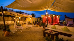 An outdoor seating area with cushioned chairs, a sofa, and a table under a large canopy.