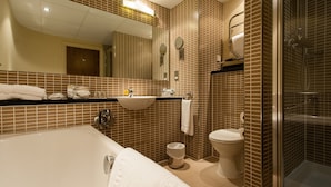 A modern bathroom with a large bathtub, a sink, a toilet, and a shower area.