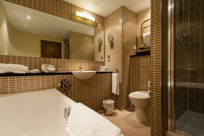 A modern bathroom with a large bathtub, a sink, a toilet, and a shower area. - Holiday Inn Dumfries by IHG (Dumfries)
