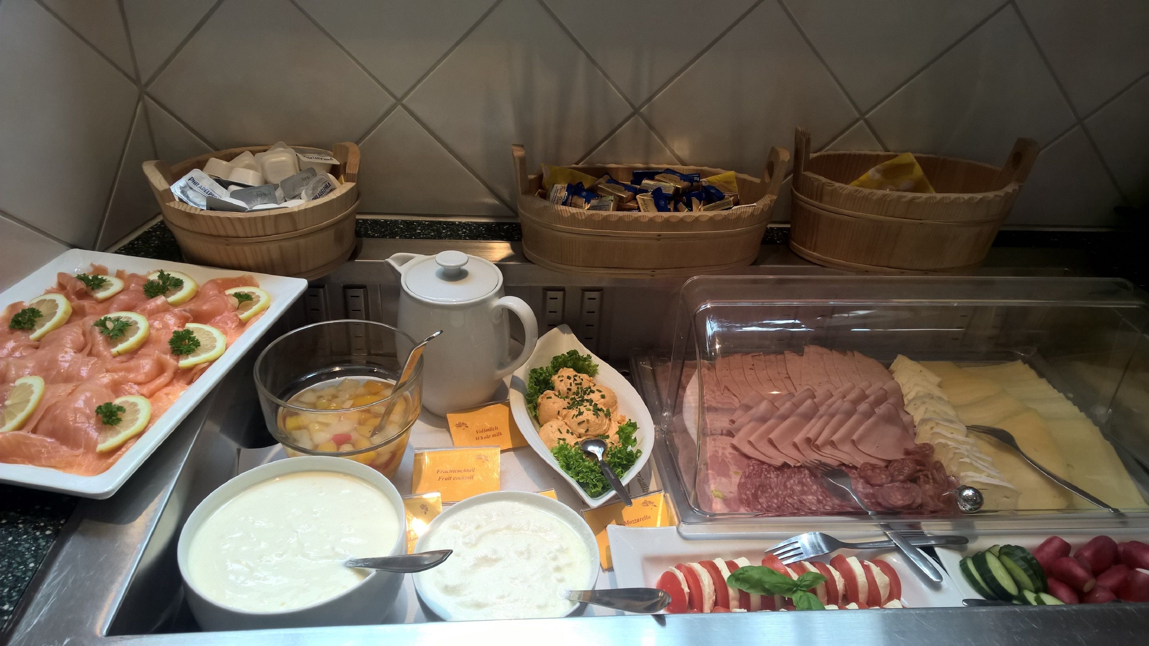 A buffet with various food items including salmon, cheese, and fruits.